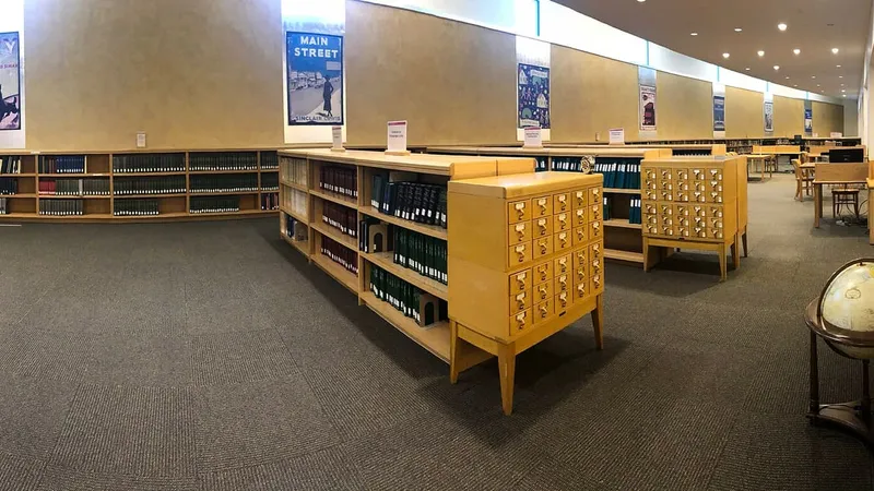 La sala della biblioteca con i tavoli di lettura e gli scaffali alle pareti