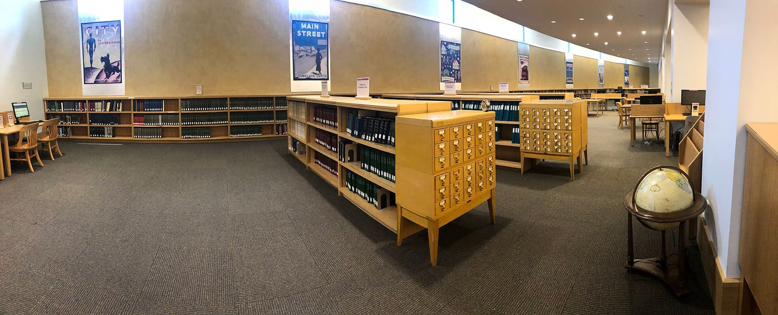La sala della biblioteca con i tavoli di lettura e gli scaffali alle pareti