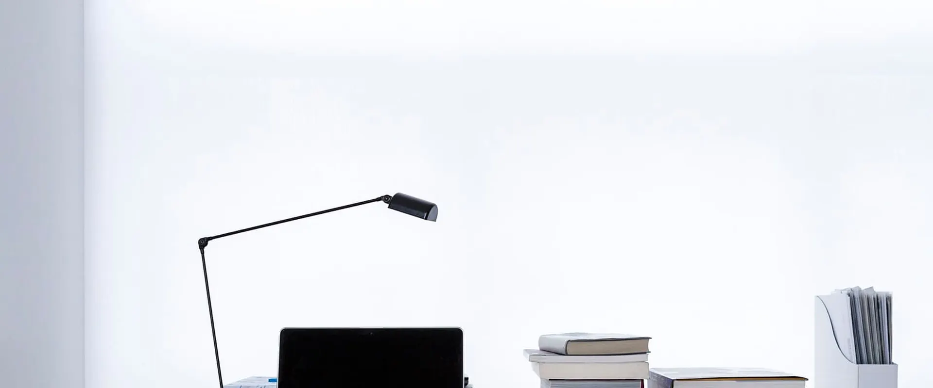 Un portatile aperto su una scrivania tra pile di libri
