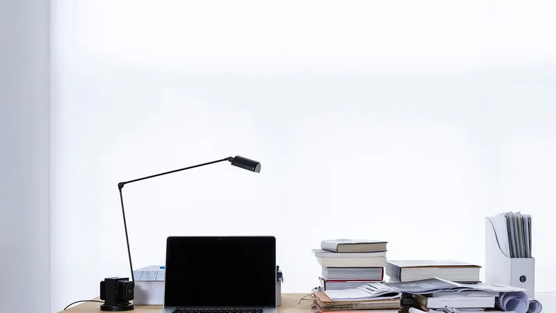 Un portatile aperto su una scrivania tra pile di libri